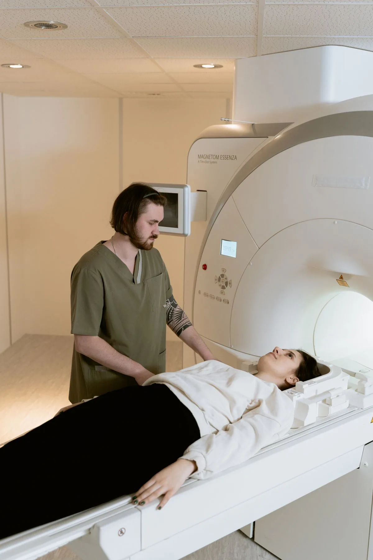 A radiology technologist helping a patient positioned on an MRI scanner table